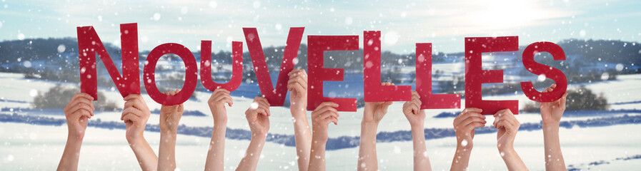 People Hands Holding Colorful French Word Nouvelles Means News. Snowy Winter Background With Snowflakes