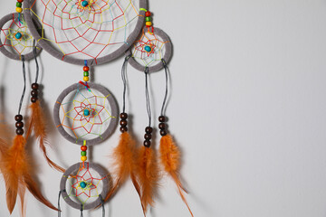 Beautiful dream catcher hanging on white wall. Space for text