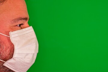 man in profile with white hygienic mask on green background