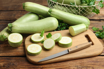 Cut and whole ripe zucchinis on wooden table