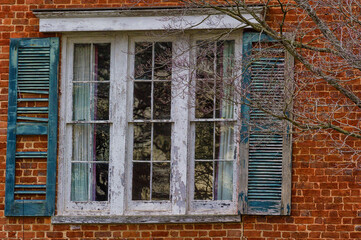 Close up of a window and shutters on a brick wall