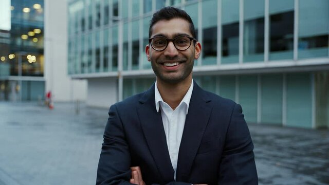 Mixed race businessman smiling standing in front of office buildings 