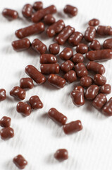 Chocolate dragee pile on white paper background