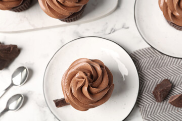 Delicious fresh chocolate cupcake on white marble table, flat lay