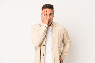 Young caucasian handsome man isolated having fun covering half of face with palm.