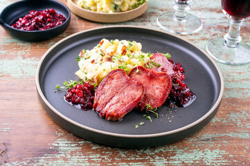 Traditionelle gebratene Kalbszunge mit Kartoffel Püree   und Preiselbeeren Relish serviert als close-up auf einem Nordic Design Teller