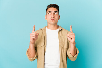 Young caucasian handsome man isolated pointing upside with opened mouth.