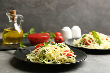 Delicious zucchini pasta with cherry tomatoes and basil served on light grey table