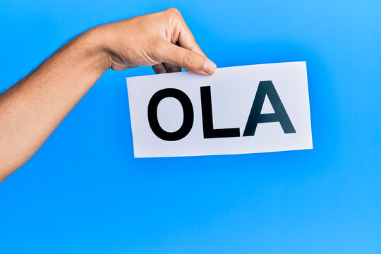 Hand of hispanic man holding ola word paper over isolated blue background.