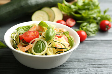 Delicious zucchini pasta with shrimps, cherry tomatoes and basil on grey wooden table