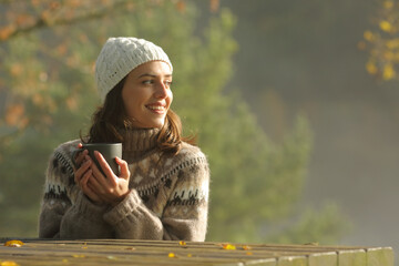 Happy woman drinking coffee looks at side in a park