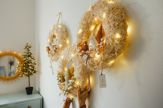 Three Handmade Christmas Wreath with Lights in Woman Hands for Winter holidays tradition, Lght garland, Natural and Ecofriendly Materials