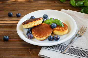Japanese fluffy pancakes with bluberries, thick souffle. Delicious breakfast on the white plate, on the wooden background.