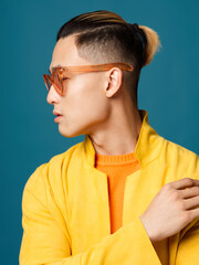 Asian man with glasses and a jacket on a blue background side view