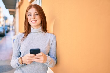 Young irish teenager girl smiling happy using smartphone at the city.