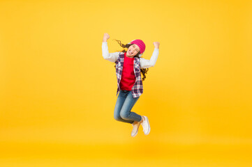 Fototapeta na wymiar Happy active kid enjoy listening and jumping to music playing in headphones yellow background, pleasure