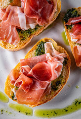 Bruschetta with prosciutto and pesto sauce on plate