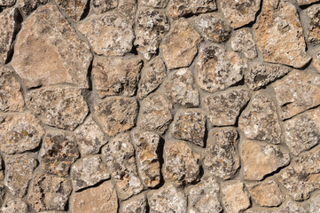 The outer facade of the building is made of natural stone of various shapes. Background texture for outdoor decoration under the Middle Ages
