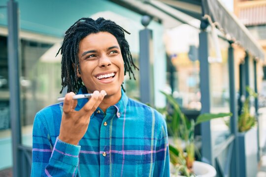 Young african american man sending audio message using smartphone at street of city.
