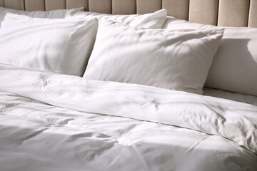 Comfortable bed with soft blanket and pillows, closeup