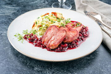 Traditional fried cured and sliced veal tongue with mashed potatoes and cranberries relish offered as close-up on a classic design plate
