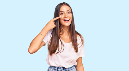 Fototapeta na wymiar Young hispanic woman wearing casual white tshirt pointing with hand finger to face and nose, smiling cheerful. beauty concept