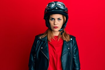 Hispanic young woman wearing motorcycle helmet with serious expression on face. simple and natural looking at the camera.