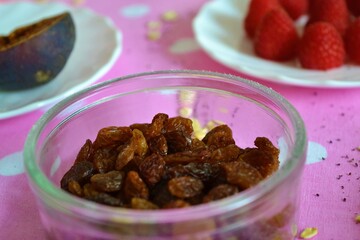 Closeup of a breakfast table with a plate of raisins, another of raspberries and a fig