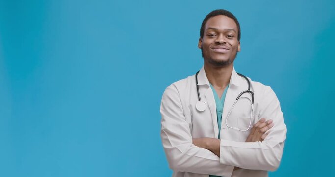 Confident professional african american doctor posing with folded arms, smiling to camera, empty space