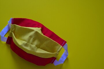 Handmade mask with the design of the Spanish flag on a yellow background symbolizing the effect of covid 19 or coronavirus on Spain