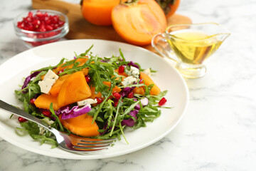 Delicious persimmon salad served on white marble table, closeup