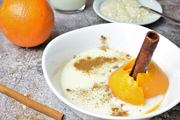 Homemade rice pudding, with a touch of citrus and cinnamon, in a white porcelain bowl on a stone with gray tones