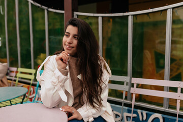 Wonderful attractive young woman waiting for friends in stylish outdoor cafe. Smiling brunette young woman with french vintage outfit resting in open-air restaurant