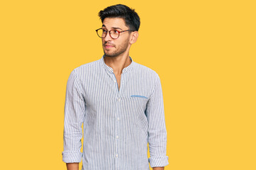 Young handsome man wearing casual clothes and glasses smiling looking to the side and staring away...
