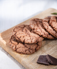 a chocolate cookies with chocolate chips on wood cutting board  on a light table
