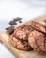 homemade chocolate cookies with chocolate chips on wood cutting board  on a light table