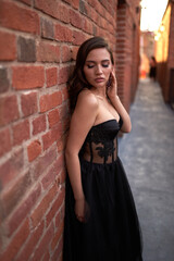 Full-length portrait of an elegant brunette woman with long hair in a black long evening dress.