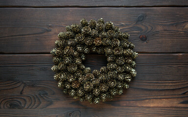 Christmas decoration DIY. hand made wreath, cone paindeg gold glitter on wooden background. wreath for door or table decoration with hole for candle