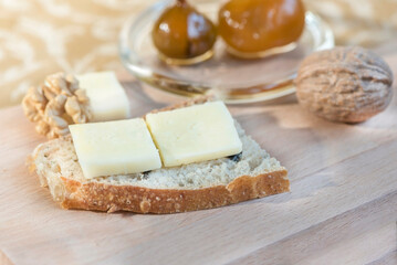 Fototapeta na wymiar A slice of whole wheat bread with cheese and fig jam on a wooden plate, close up, macro photography