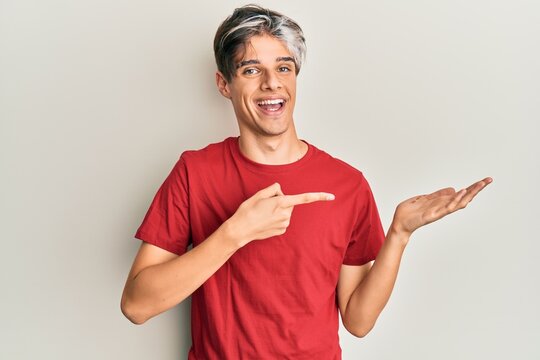 Young hispanic man wearing casual clothes amazed and smiling to the camera while presenting with hand and pointing with finger.