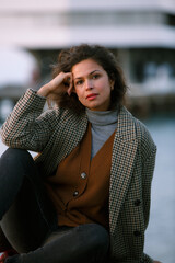 portrait of a woman of mixed race in the city's seaport, dressed in a coat and woolen items