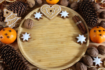 Christmas background with gingerbread, nuts, cinnamon sticks, pine cones and mandarins