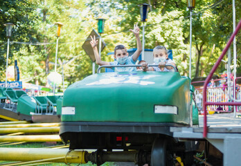 children in medical masks ride the attraction