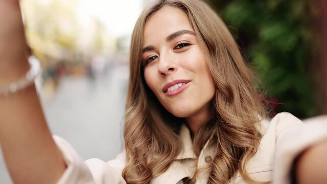 Close up pov of woman's face, using smart phone, recording selfie, wile talking on smartphone. POV of young beautiful woman standing outdoor and talking via web cam. Videochat concept