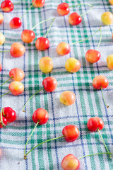 Naklejka na ściany i meble Fresh homemade ripe sweet cherries on squared fabric background. Summer still life