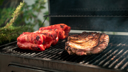 Cooking pork ribs with red peppers on BBQ grill. Cook a delicious grilled meat.