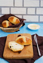 Traditional Easter cross buns made from yeast dough on a wooden board against a blue concrete background. Easter holiday, concept. Easter recipes.