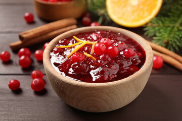 Cranberry sauce with orange peel on wooden table, closeup