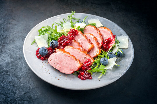 Modern Style gourmet Entenbrust Filet mit Rucola Salat und Preiselbeer Relish serviert als close-up auf einem Design Teller mit Textfreiraum