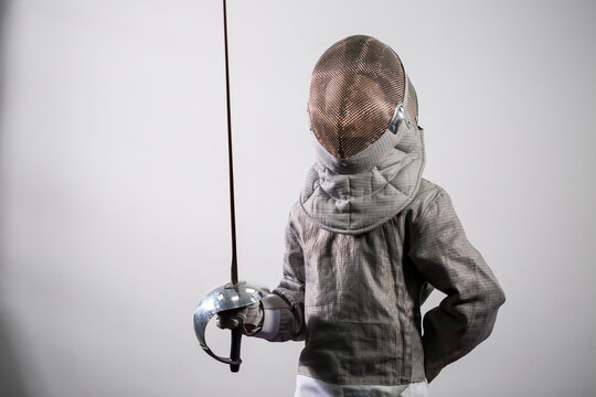 A girl in a fencing suit with a sword in hand. Young female model practicing and exercising. Sports, healthy lifestyle.